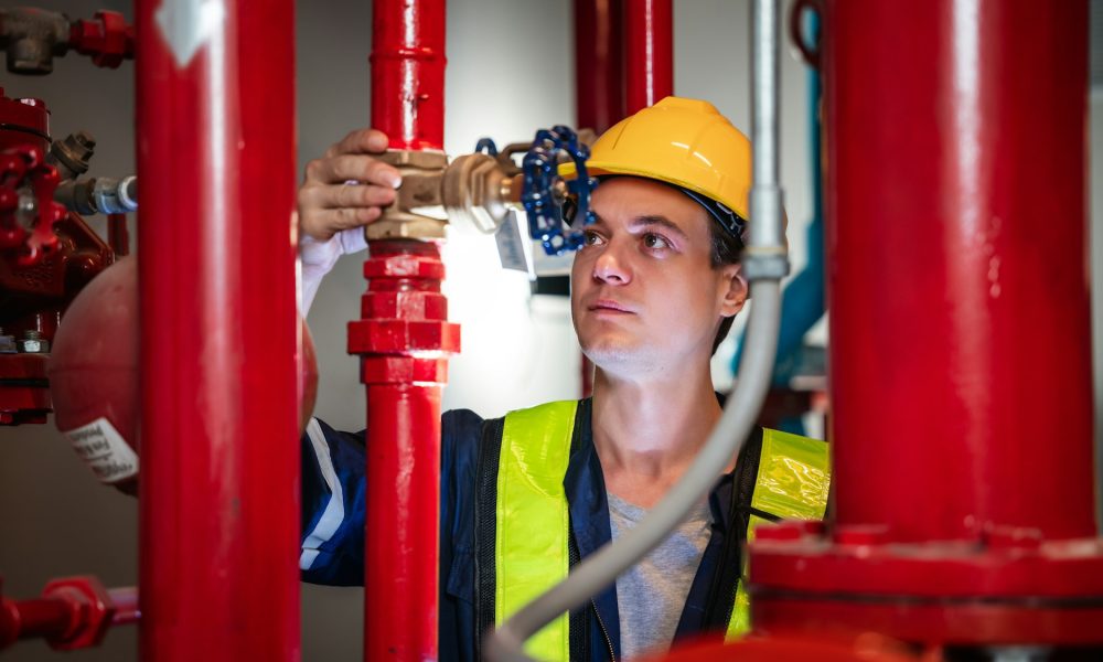 A team of engineers is examining the plumbing and water valves inside an industrial facility.
