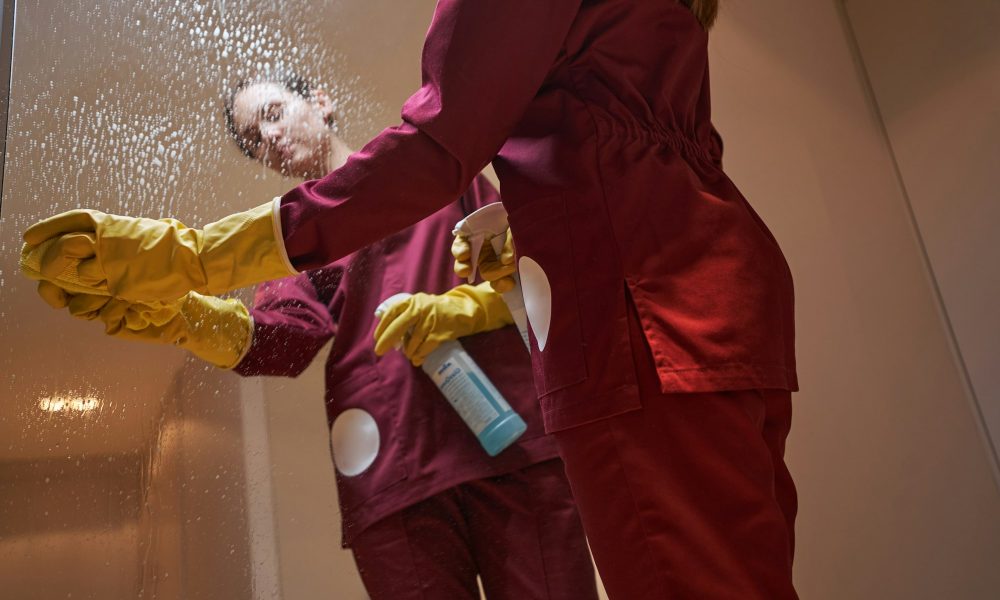Experienced cleaner cleaning mirrored surface in apartment hallway